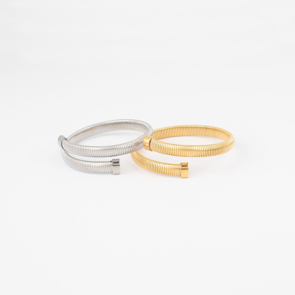 amia Cuff Bracelets in gold and silver stainless side by side on a white background.
