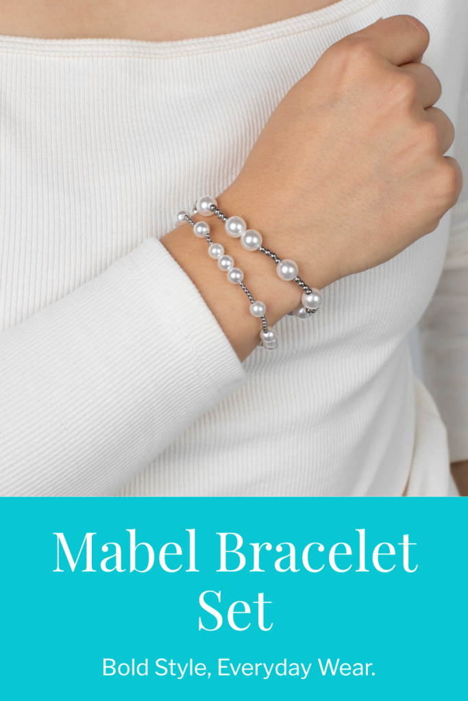 A close-up of the Mabel Bracelet Set in gold stainless—two stretchy beaded bracelets featuring faux pearls and small gold beads, styled on a wrist with a cozy neutral jacket.
The Mabel Bracelet Set in stainless steel, worn with a white ribbed top. The layered bracelets blend luminous faux pearls and silver beads for a timeless stacked look.